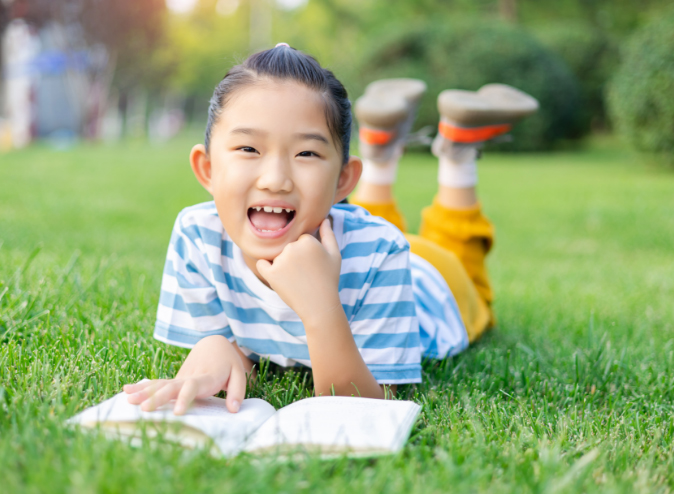 A student reads while laying in the grass 